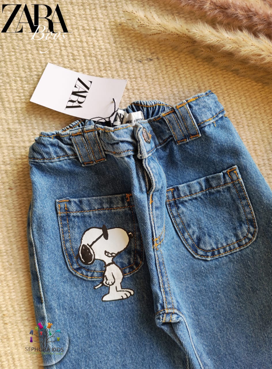 Blue jeans with Snoopy designs on a textured surface