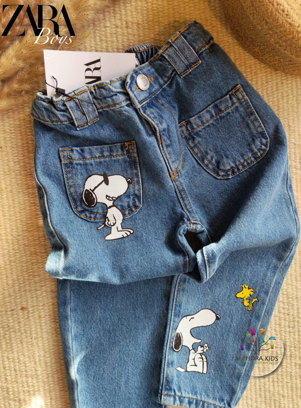 Blue jeans with Snoopy designs on a textured surface