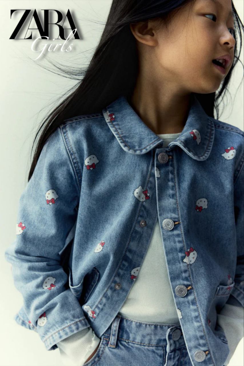Child wearing a denim jacket with embroidered details, standing against a plain background.