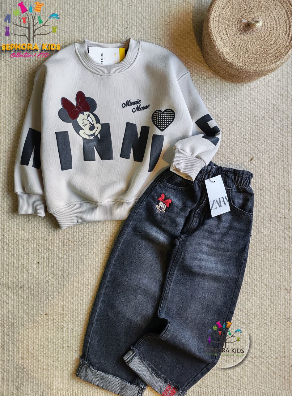 Children's outfit with a gray sweatshirt and black jeans featuring Minnie Mouse design on a textured surface.