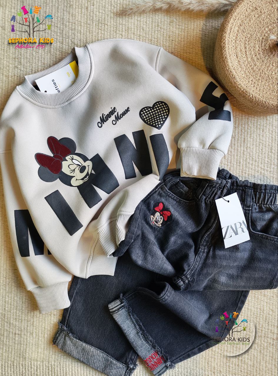Children's clothing set with sweatshirt and jeans on a textured surface, featuring brand labels.