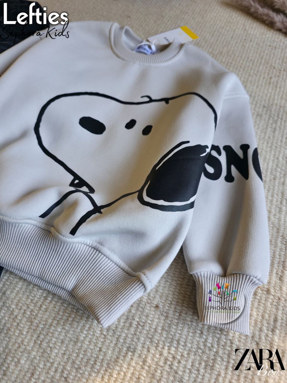 White sweatshirt with black graphic design on a beige surface, 