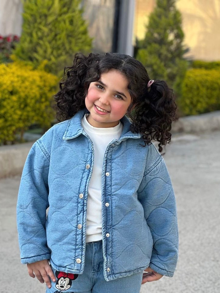 Child wearing a blue denim outfit with a white shirt and sneakers on a street.